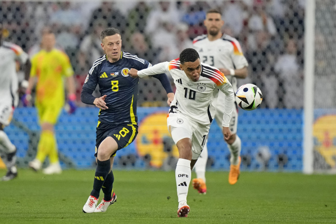 Tiền vệ Jamal Musiala (số 10) vượt qua cầu thủ Scotland Callum McGregor ở trận ra quân bảng A trên sân Allianz, Munich ngày 14/6. Ảnh: AP